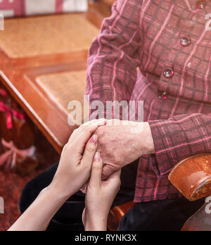 Asien Mädchen im Teenageralter Pflegeperson Holding grandma Hände, helfende Pflege für ältere Menschen leben mit dunklem Hintergrund, Nahaufnahme, Kopieren, 7/8 Stockfoto