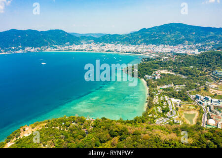 Ansicht von oben, beeindruckende Luftaufnahme von Patong City Skyline in der Entfernung und der schönen Tri Trang Strand gebadet durch ein Türkis und klaren Meer. Stockfoto