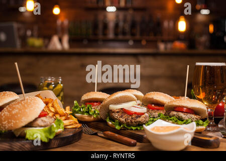 Kühles Bier neben einer Vielzahl von Burgers in Vintage Restaurant. Gebratene Kartoffeln. Stockfoto