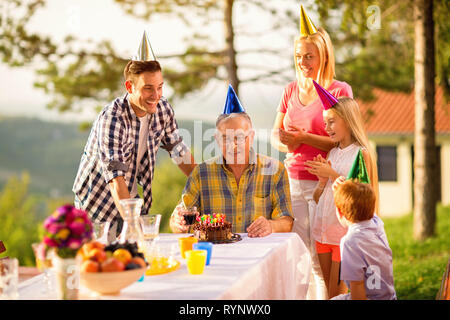 Familie feiert Geburtstag Großvater zusammen im Garten Stockfoto