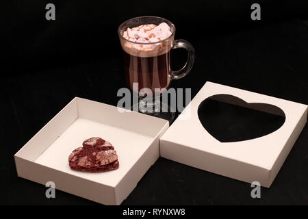 Hot Drink in ein Glas Schale mit rosa Marshmallows und White Box mit transparentem Deckel in der Form von Herzen mit Cookies Stockfoto