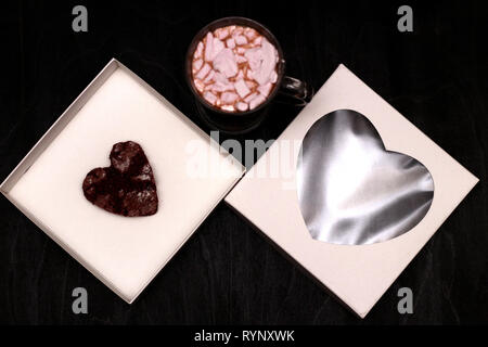 Hot Drink in ein Glas Schale mit rosa Marshmallows und White Box mit transparentem Deckel in der Form von Herzen mit Cookies Stockfoto