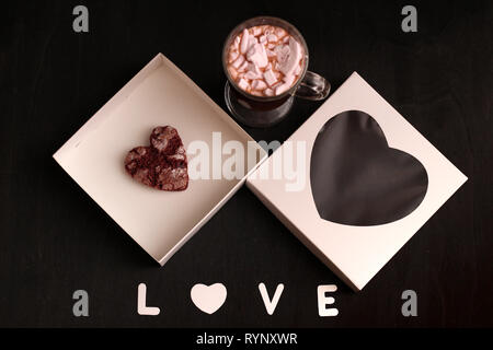 Hot Drink in ein Glas Schale mit rosa Marshmallows und White Box mit transparentem Deckel in der Form von Herzen mit Cookies Stockfoto