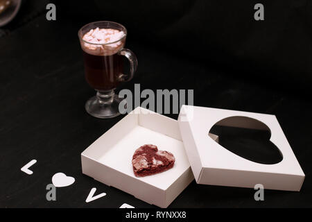 Hot Drink in ein Glas Schale mit rosa Marshmallows und White Box mit transparentem Deckel in der Form von Herzen mit Cookies Stockfoto