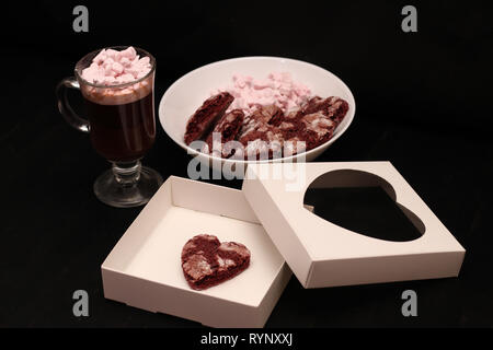 Hot Drink in ein Glas Schale mit rosa Marshmallows und White Box mit transparentem Deckel in der Form von Herzen mit Cookies Stockfoto