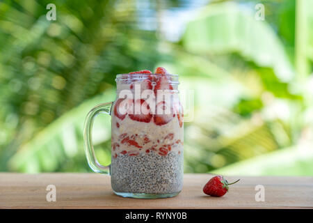 Mandelmilch chia Milchreis mit frischen roten Erdbeeren, Goji Beeren und Haferflocken in einem Glas mug. Vegan raw Frühstück. Chia Samen und frisch geschnitten fr Stockfoto