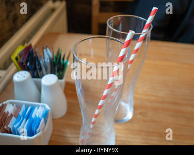 Zwei Getränke Gläser mit streifiger Papier Trinkhalme auf einer hölzernen cafe Tabelle Stockfoto