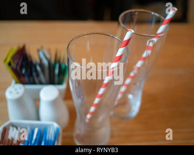 Zwei Getränke Gläser mit streifiger Papier Trinkhalme auf einer hölzernen cafe Tabelle Stockfoto