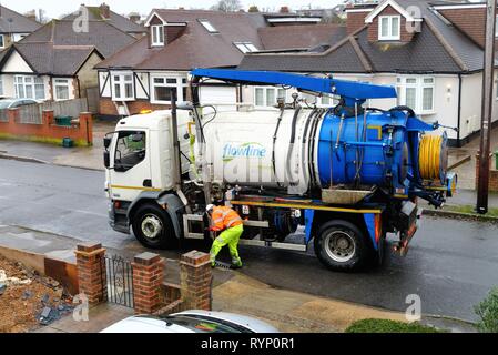 Ein Arbeiter clearing Abflüsse mit einem großen Saug Lkw in einer Wohnstraße in Shepperton Surrey England Großbritannien Stockfoto