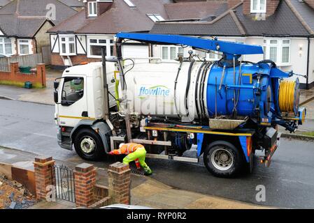 Ein Arbeiter clearing Abflüsse mit einem großen Saug Lkw in einer Wohnstraße in Shepperton Surrey England Großbritannien Stockfoto