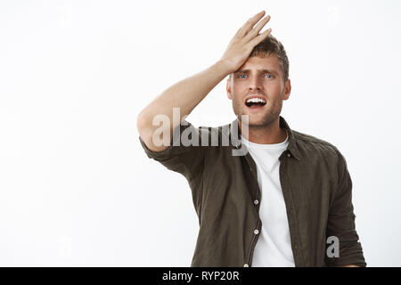 Taille - geschossen von vergesslich cute blonde Mann mit blauen Augen stanzen Stirn von Bedauern und Enttäuschung, frustriert, verärgert Grimasse, offenen Mund Stockfoto