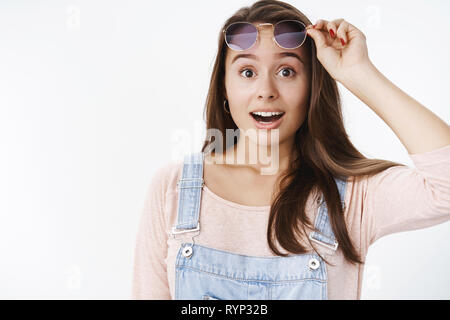 Studio shot von überrascht attraktive junge Frau unerwartete zu sehen Freund in Masse, Sonnenbrille, Augenbrauen und Mund in Lächeln von Stockfoto