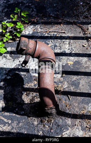 Alte Ölleitung im Schatten eines Zauns Stockfoto