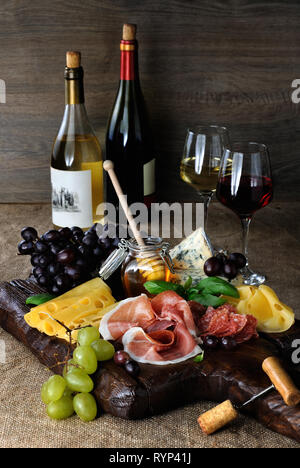 Antipasto catering Plattenteller mit ruckartiger Speck, Schinken, Salami, Käse und Trauben auf einem hölzernen Hintergrund Stockfoto