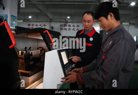 Chongqing, China. 14 Mär, 2019. Ein Student (R) aus einer beruflichen Bildung Schule lernt eine Drehmaschine im yongchuan Bezirk Chongqing zu betreiben, im Südwesten von China, 14. März 2019. Die lokalen Behörden bei der Verbesserung der beruflichen Bildung auf die Bedürfnisse des Arbeitsmarktes in den letzten Jahren gerecht zu werden. Credit: Wang Quanchao/Xinhua/Alamy leben Nachrichten Stockfoto