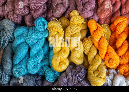 Ein Haufen von natürlichen Strickgarn von gelb, orange, blaue und braune Farben ist betriebsbereit. Rote, blaue und braune Farben Stockfoto