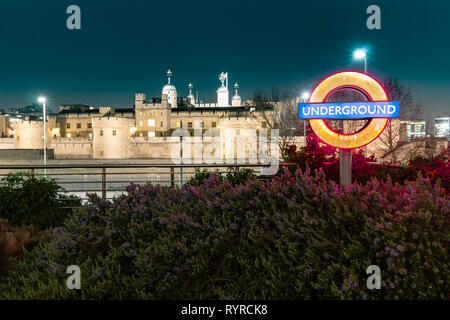 Tower Hill, London, England, 14. März 2019. Eine berühmte Londoner U-beleuchteten Zeichen aus Seite Tower Hill Station mit dem Tower von London im b Stockfoto