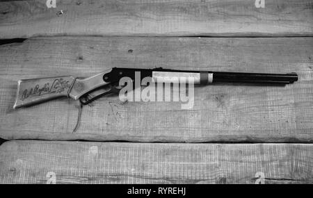 Red Ryder BB Gewehr auf Holz- Hintergrund. Schwarz und Weiß. Overhead shot. Stockfoto