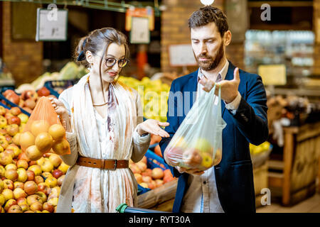 Mann und Frau Kauf von Lebensmitteln mit Eco und Plastikbeutel im Supermarkt. Das Konzept der Verwendung von eco Beutel während des Einkaufs Stockfoto