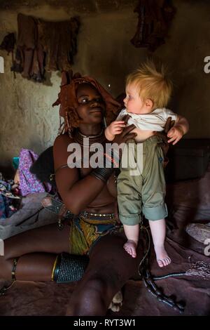 Himba Frau mit einem weißen touristische Baby, Kaokoveld, Namibia Stockfoto