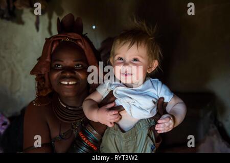 Himba Frau mit einem weißen touristische Baby, Kaokoveld, Namibia Stockfoto