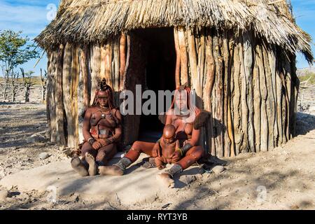 Himba Frauen vor ihrer Hütte, Kaokoveld, Namibia Stockfoto