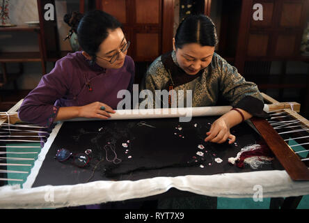 (190315) - NANJING, März 15, 2019 (Xinhua) - Fu Xianghong (R) und ihre Tochter Fu Hanlu kommuniziert über sticken Techniken in Guangfu Stadt Wuzhong District von Suzhou in der ostchinesischen Provinz Jiangsu, am 14. März 2019. Fu Xianghong und ihre Tochter Fu Hanlu waren von einer langen Linie der Stickerei. Im Jahr 2015 Fu Xianghong war als Vertreter der Meister der Suzhou Stickerei, die als ein immaterieller Suzhou's Erbe aufgeführt wurde ernannt. Ihre Werke von einzigartigen Stil mit Zweckmäßigkeit und Kunstfertigkeit wurden jemals während der Fashion Week in Peking und Paris Fashion Week präsentiert. Ihre Tochter Fu Hanl Stockfoto