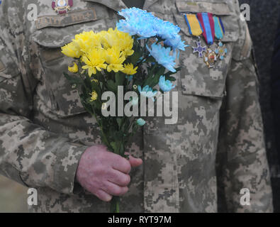 Kiew, Ukraine. 14 Mär, 2019. Ein Offizier in der Armee gesehen mit einem Blumenstrauß in der Hand während der Feierlichkeiten zum Tag der ukrainischen Freiwilligen in Kiew zu markieren. Ukraine feiert Volunteer Day, die zu Ehren der Bürger, die sich freiwillig entschieden, den Zustand von russischen Aggression zu schützen gegründet wurde. Es war an diesem Tag vor fünf Jahren, dass die ersten 500 Freiwilligen aus der 'Selbst-Verteidigung der Maidan'' sozialen Bewegung in der "Nowyje Petrivtsi Trainingsplatz angekommen einen freiwilligen Bataillon, das in der Region Dnipropetrovsk Anfang April 2014 verlegt und wurde genannt Dnipro-2 zu bilden. Stockfoto