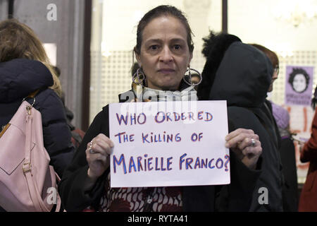 London, Greater London, UK. 14 Mär, 2019. Eine Frau gesehen, die ein Plakat, das liest, befohlen, das Töten von Marielle Franco?, während der gebetswache. Demonstranten vor der Brasilianischen Botschaft in London das Leben und das Vermächtnis des Brasilianischen Aktivist Marielle Franco, war ein ausgesprochener Kritiker der Polizeibrutalität und außergerichtliche Tötungen gegen Favela Bewohnerinnen zu Ehren versammelt. Franco wurde ermordet wegen ihrer politischen Aktivitäten zusammen mit ihrem Fahrer Anderson Gomes am 14. März in Rio de Janeiro, Brasilien 2018. Während der gebetswache Redner sprachen die Assistenten und behauptete, Justiz und d Stockfoto