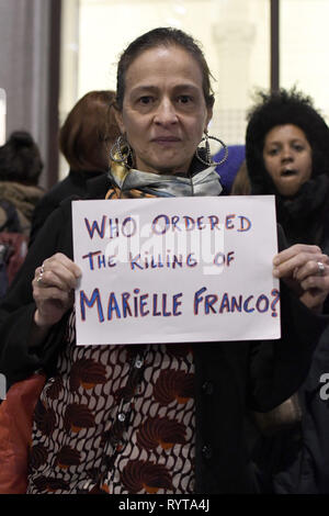 London, Greater London, UK. 14 Mär, 2019. Eine Frau gesehen, die ein Plakat, das liest, befohlen, das Töten von Marielle Franco?, während der gebetswache. Demonstranten vor der Brasilianischen Botschaft in London das Leben und das Vermächtnis des Brasilianischen Aktivist Marielle Franco, war ein ausgesprochener Kritiker der Polizeibrutalität und außergerichtliche Tötungen gegen Favela Bewohnerinnen zu Ehren versammelt. Franco wurde ermordet wegen ihrer politischen Aktivitäten zusammen mit ihrem Fahrer Anderson Gomes am 14. März in Rio de Janeiro, Brasilien 2018. Während der gebetswache Redner sprachen die Assistenten und behauptete, Justiz und d Stockfoto