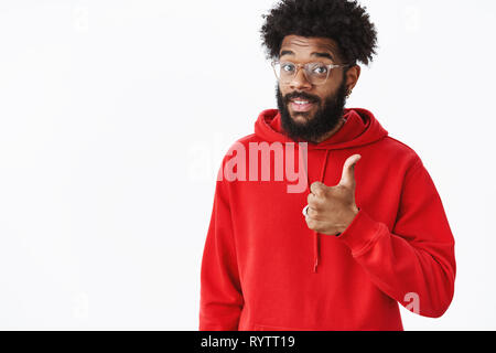 Das ist guter Inhalt. Portrait von zufriedenen gut aussehende afrikanische amerikanische Musikproduzent mit Bart in Gläsern und Rot hoodie mit Daumen Heben Stockfoto