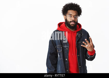 Stilvolle städtischen gut aussehende afrikanischen bärtigen Kerl mit Afro Frisur und Piercing in Gläsern mit Nummer vier mit Fingern und Kamera Stockfoto