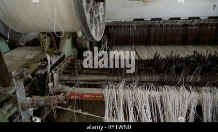 Alte weisse Fäden des Alten Nähmaschine in der alten Textilfabrik in Kreenholm Stockfoto