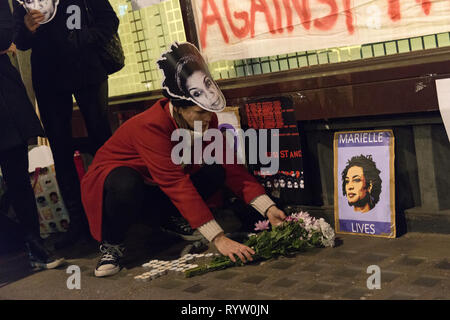 Eine Frau gesehen die Blumen neben einem Plakat mit Marielle Franco Bild. Die Demonstranten versammelten sich vor der Brasilianischen Botschaft in London das Leben und das Vermächtnis des Brasilianischen Aktivist Marielle Franco, war ein ausgesprochener Kritiker der Polizeibrutalität und außergerichtliche Tötungen gegen Favela Bewohnerinnen zu ehren. Franco wurde ermordet wegen ihrer politischen Aktivitäten zusammen mit ihrem Fahrer Anderson Gomes am 14. März in Rio de Janeiro, Brasilien 2018. Während der gebetswache Redner sprachen die Assistenten und beanspruchten Gerechtigkeit und forderten das Ende der Straflosigkeit in Francos Verbrechen. Stockfoto