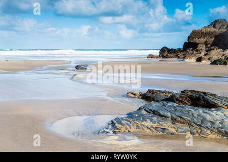 Eine frische helle und luftige Tag in einer ruhigen sandigen Bucht an der Nordküste von Cornwall mit Sand, Pools und Felsen im Vordergrund. Stockfoto