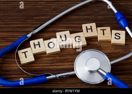 'Wort Gedanken' auf Holzklötze zwischen Stethoskop geschrieben Stockfoto