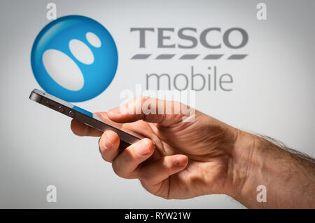Ein Mann mit einem Handy vor der Tesco Mobile Network anmelden Stockfoto