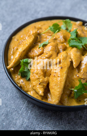 Schließen oben mit Blick auf eine Schüssel mit Chicken kurma Curry. Schüssel mit dicken indische Curry. Schüssel mit dicken Chicken Korma curry mit grauen Hintergrund. Stockfoto