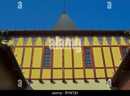 Blick auf alte gelbe Wand mit zwei Fenstern und quadratischen Turm auf einem Gebäude Stockfoto