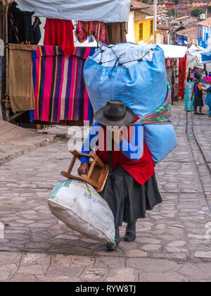 Pisac, Peru - 19. Mai 2016: Die Frau mit den grossen blauen Sack auf dem Rücken auf der Straße von Pisac. Lateinamerika. Stockfoto