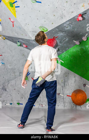 Kletterer Mann schob seine Hände in eine Tasche von Magnesia Pulver hinter seinem Rücken in der Boulder Halle Stockfoto