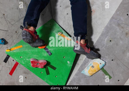 Rocky Schuh auf einem kleinen, kargen Snare steht mit der Spitze der Socke in close-up an der Kletterwand im Zimmer Stockfoto