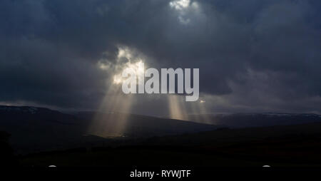 Sonnenstrahlen kommen durch Sturm Wolken über Askrigg in den Yorkshire Dales, UK. Stockfoto