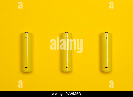Blick von oben auf die 3 gelbe AA Alkali oder NiMH-Akkus auf gelbem Hintergrund Stockfoto