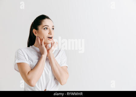 Wow. Schöne weibliche Hälfte - Länge vorne portrait isoliert auf Grau studio Hintergrund. Junge emotionale überrascht stehende Frau mit offenen Mund. Menschliche Gefühle, Mimik Konzept. Stockfoto