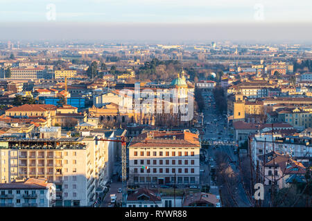 Reisen nach Italien - Blick auf die Stadt (Citta Bassa) bis zum Bahnhof und Flughafen von der Oberstadt von Bergamo, Lombardei bei Sonnenuntergang Stockfoto