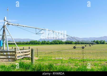 Große Drehmittelpunkt Bewässerungssystem läuft auf einem Bauernhof in Canterbury, Neuseeland. Lange bewegliche Booms der Wasserversorgung Anlagen erstrecken sich von f Stockfoto