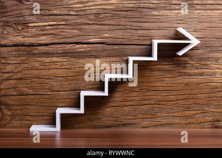 In der Nähe von Weißen zunehmende Treppe Pfeil auf Holz- Hintergrund Stockfoto