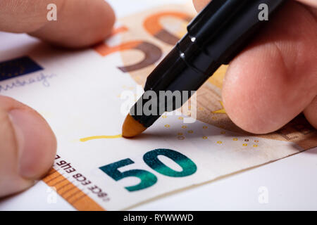 Nahaufnahme der Hand schreiben Auf Banknote mit gelben Marker Stockfoto