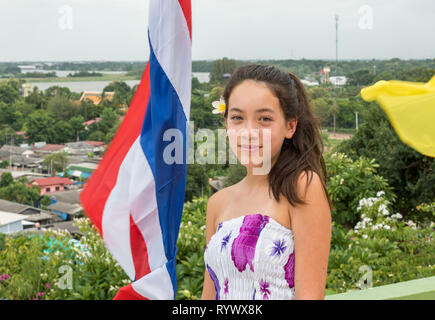 Lächelnd jugendlich stand vor der Thailändischen Fahne mit der Stadt im Hintergrund Stockfoto